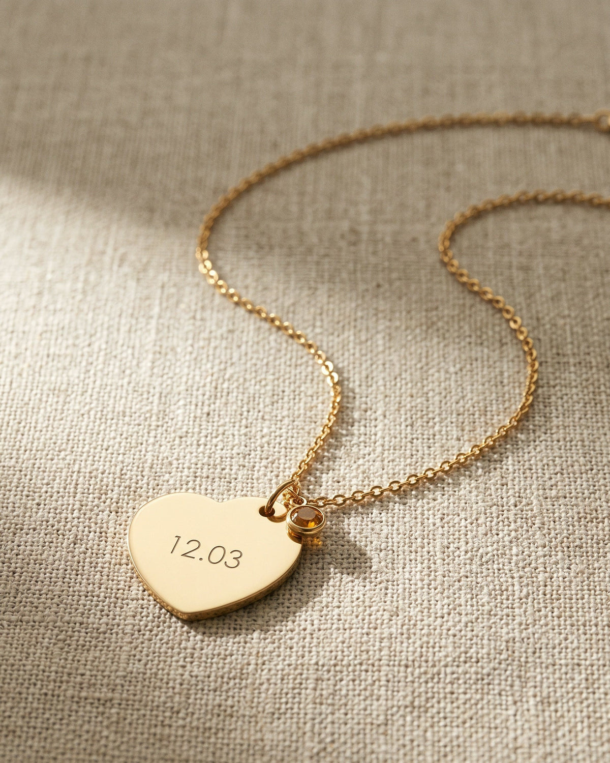 Nº 12, ketting met hart 20 bij 25 mm, goudkleurig roestvrij staal, op linnen ondergrond